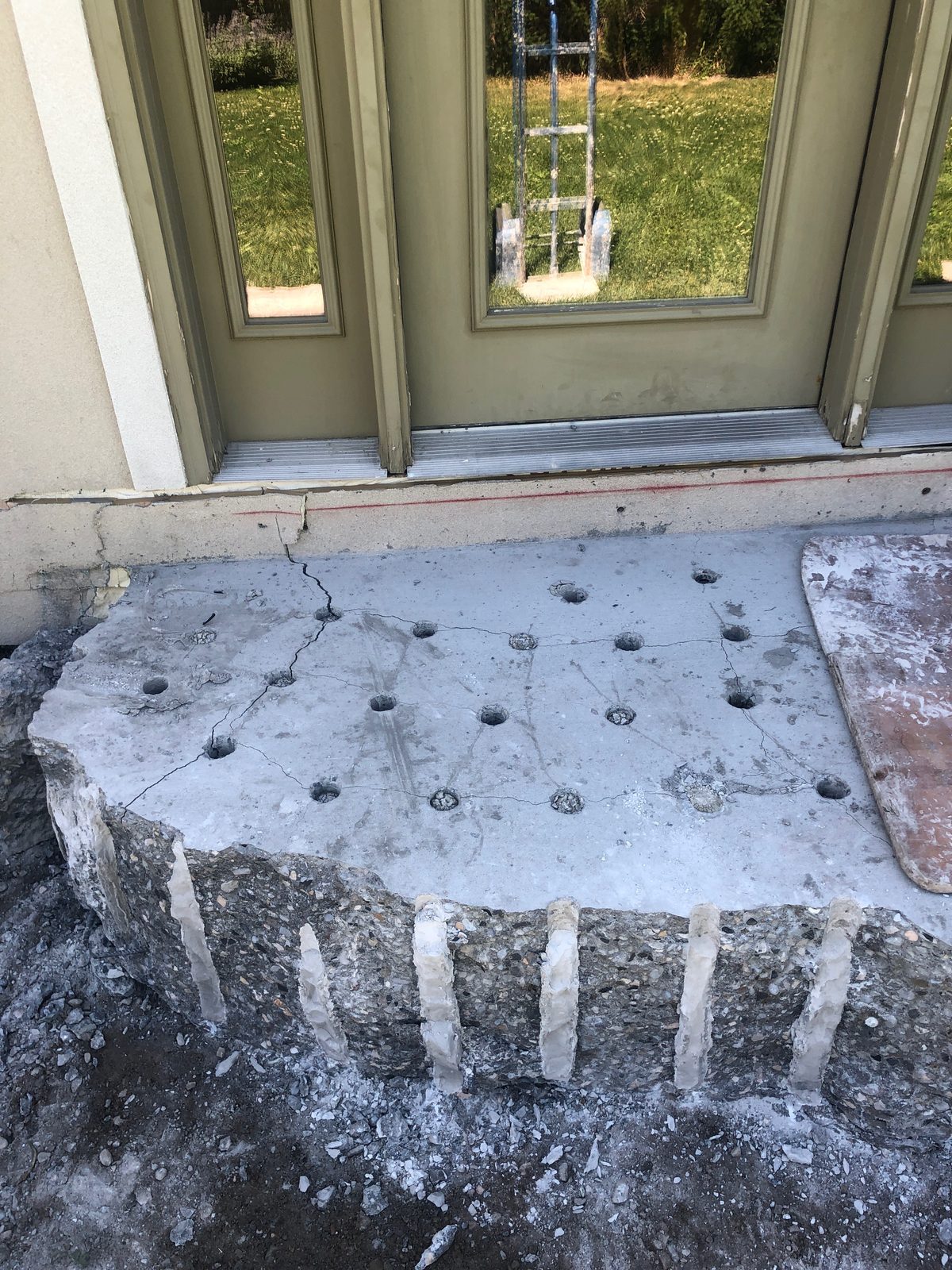 A grid of holes drilled into a concrete slab with the front face split cleanly off using Dexpan expansive grout, on a Salt Lake area job