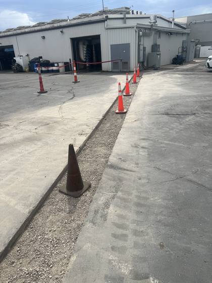 Saw cutting a trench line behind a commercial building